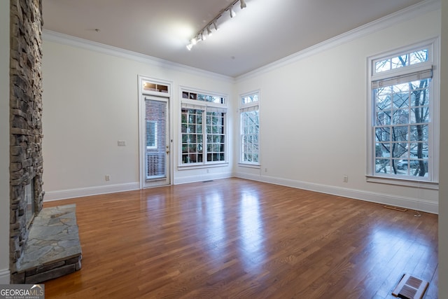 unfurnished room featuring crown molding, dark hardwood / wood-style floors, a fireplace, and a wealth of natural light