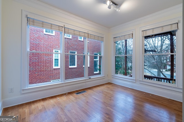 unfurnished room featuring crown molding, wood-type flooring, and track lighting