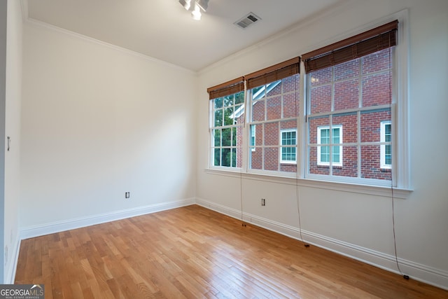 spare room with ornamental molding and light hardwood / wood-style floors