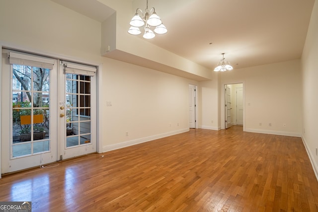 empty room featuring an inviting chandelier, hardwood / wood-style floors, and french doors