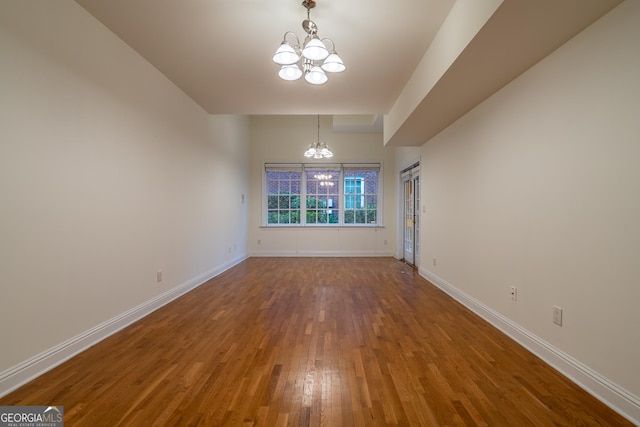 unfurnished dining area with hardwood / wood-style floors and a chandelier