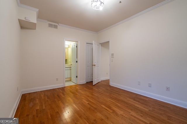 unfurnished bedroom featuring crown molding, connected bathroom, and hardwood / wood-style floors