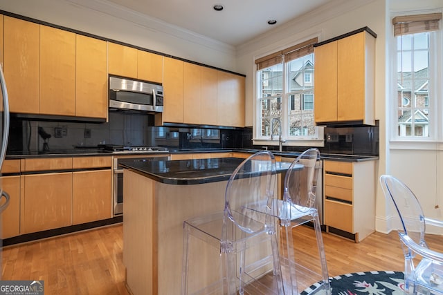 kitchen featuring backsplash, a center island, stainless steel appliances, crown molding, and light hardwood / wood-style flooring