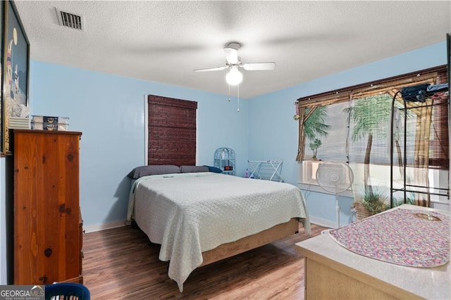 bedroom with dark hardwood / wood-style flooring, ceiling fan, and a textured ceiling