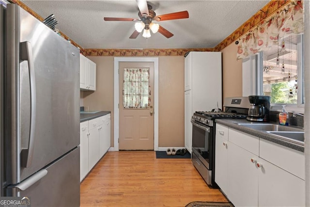 kitchen featuring sink, white cabinetry, stainless steel appliances, a textured ceiling, and light wood-type flooring