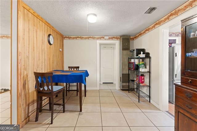 tiled dining area with a textured ceiling and wood walls