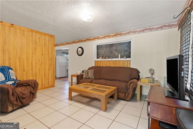 living room with light tile patterned floors, wooden walls, and a textured ceiling