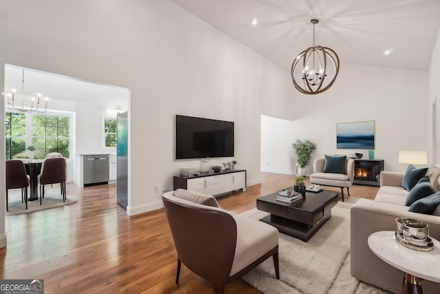 living room featuring a high ceiling, an inviting chandelier, and light hardwood / wood-style floors