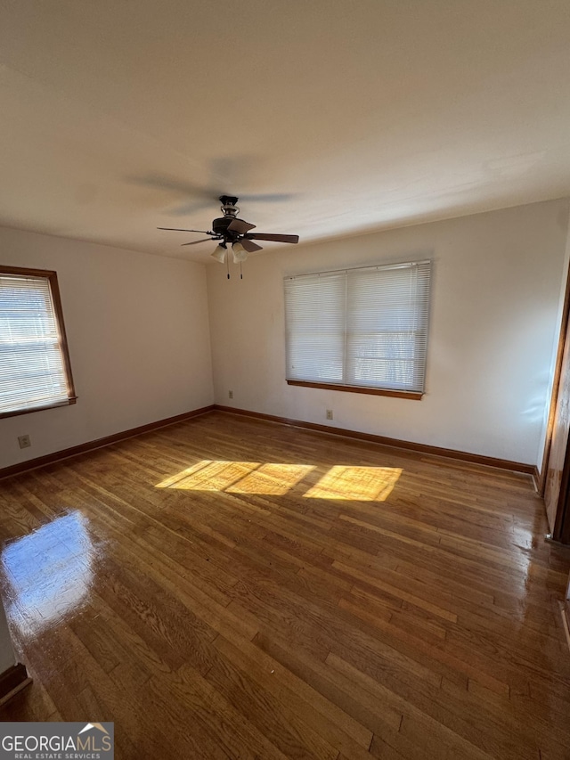 empty room with ceiling fan and dark hardwood / wood-style flooring