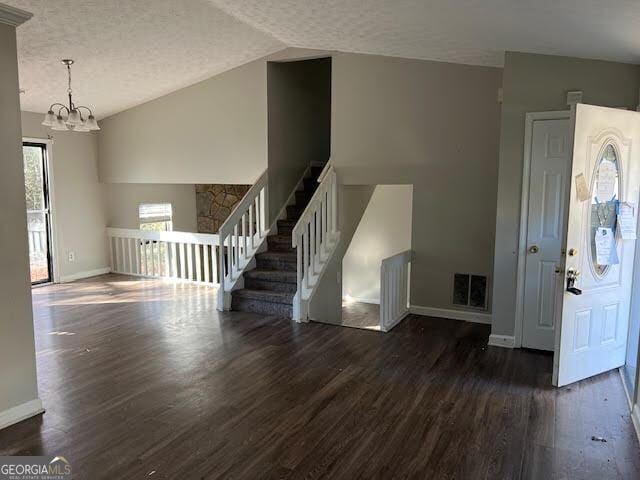 entrance foyer featuring vaulted ceiling, dark wood-type flooring, a notable chandelier, and a textured ceiling