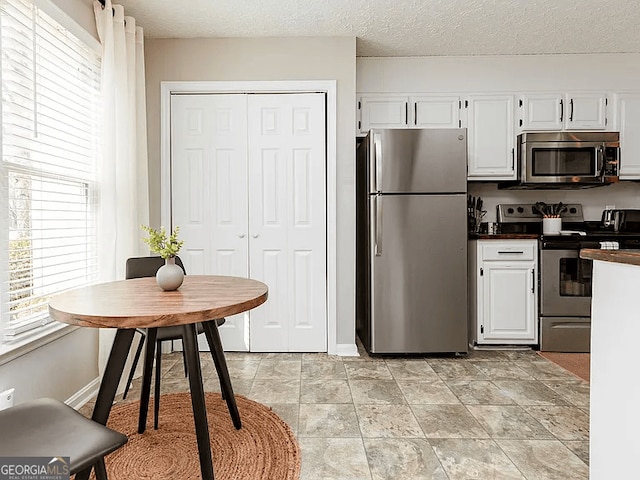 kitchen featuring a textured ceiling, white cabinets, and appliances with stainless steel finishes