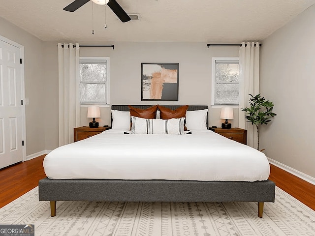 bedroom featuring multiple windows, hardwood / wood-style floors, and ceiling fan