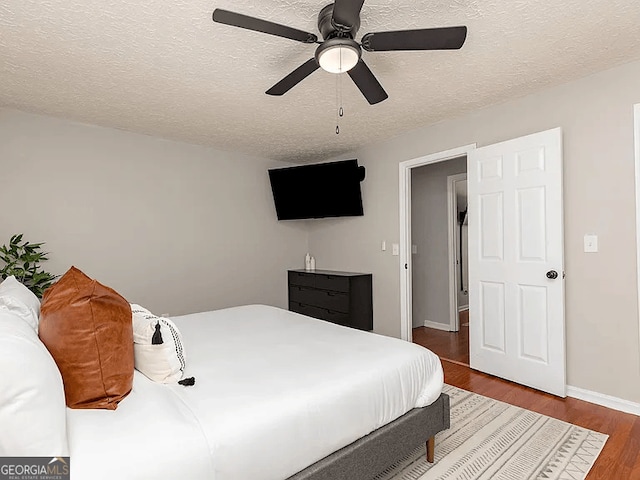 bedroom featuring ceiling fan, wood-type flooring, and a textured ceiling