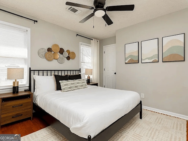 bedroom featuring ceiling fan, hardwood / wood-style flooring, and a textured ceiling