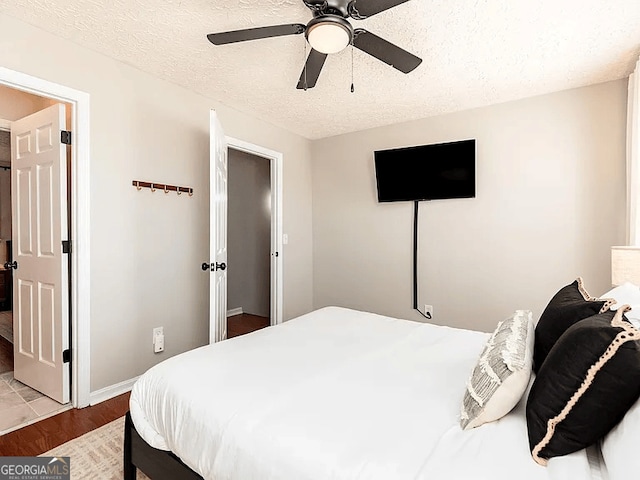 bedroom with ceiling fan, light hardwood / wood-style floors, and a textured ceiling