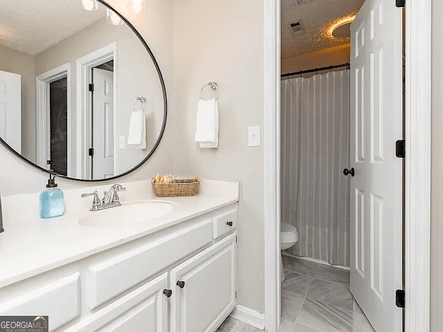 bathroom with vanity, toilet, and a textured ceiling