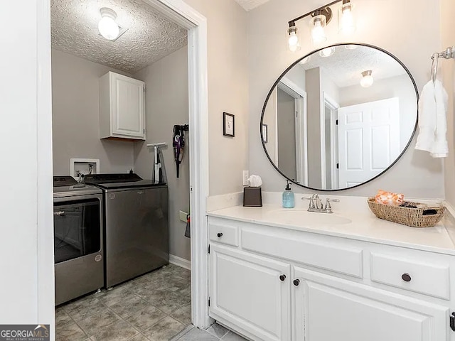 laundry area with cabinets, separate washer and dryer, sink, and a textured ceiling