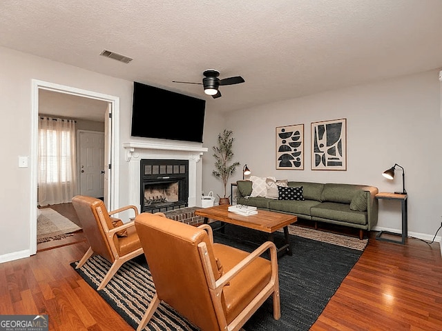 living room featuring wood-type flooring, ceiling fan, and a textured ceiling