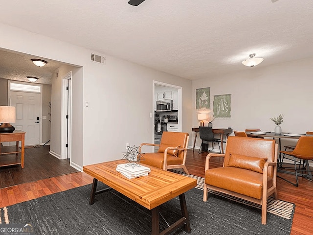 living room featuring dark hardwood / wood-style flooring and a textured ceiling