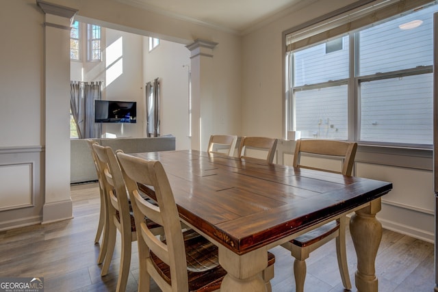 dining space with ornamental molding, a wealth of natural light, light hardwood / wood-style flooring, and ornate columns