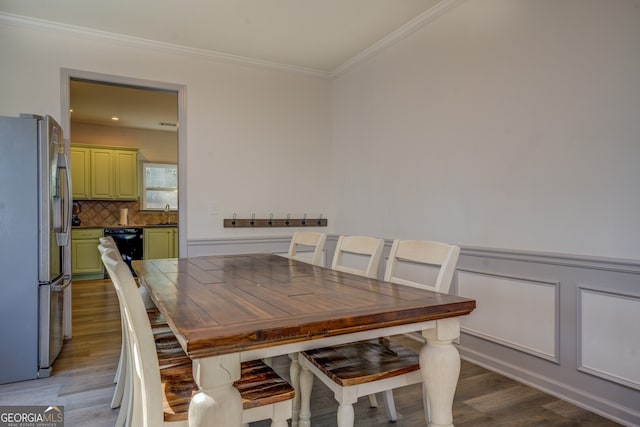 dining area with wood-type flooring, ornamental molding, and sink