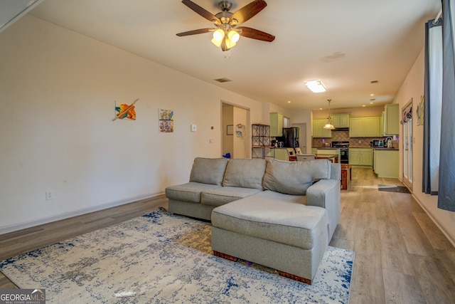 living room featuring ceiling fan and light hardwood / wood-style floors