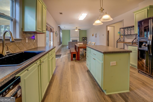 kitchen featuring sink, green cabinetry, hanging light fixtures, a kitchen island, and black appliances