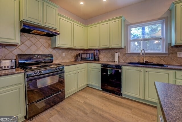 kitchen featuring black appliances, sink, decorative backsplash, green cabinetry, and light wood-type flooring