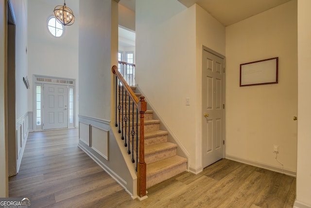 entryway with an inviting chandelier, a towering ceiling, and wood-type flooring