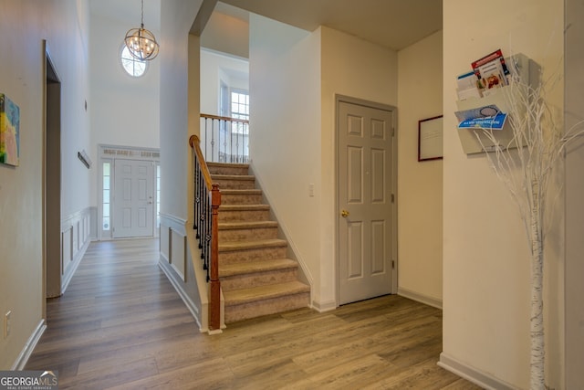 stairs with hardwood / wood-style flooring, a chandelier, and a towering ceiling