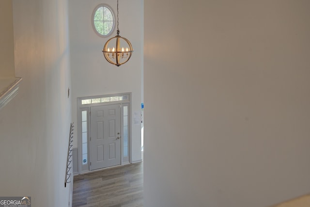 foyer entrance featuring a towering ceiling, a chandelier, and light wood-type flooring