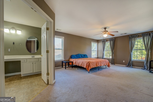 carpeted bedroom with multiple windows, ensuite bath, and ceiling fan