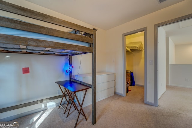 bedroom with a walk in closet and light colored carpet