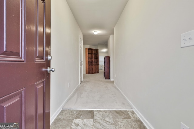 hallway featuring baseboards and light colored carpet