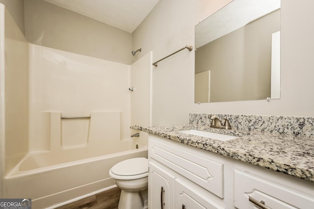 full bathroom with hardwood / wood-style floors, vanity, toilet, bathing tub / shower combination, and a textured ceiling