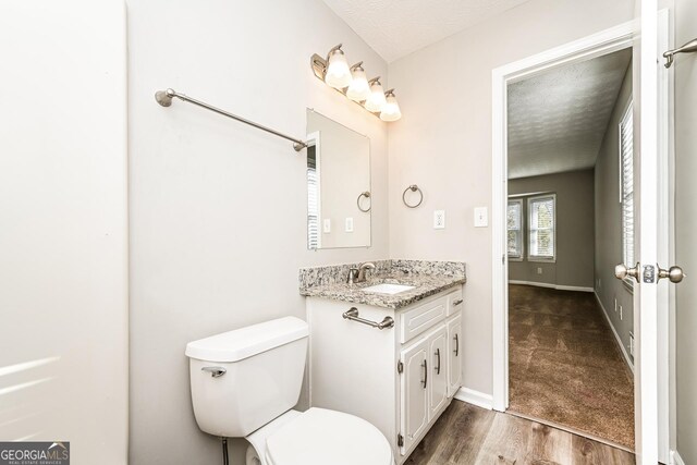 bathroom featuring hardwood / wood-style flooring, vanity, a textured ceiling, and toilet