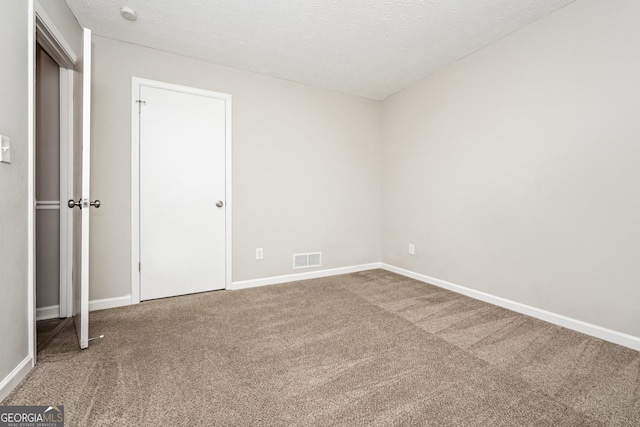 spare room featuring a textured ceiling and carpet