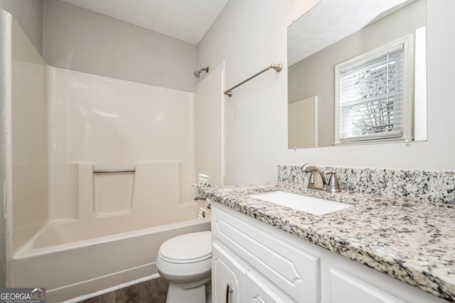 full bathroom featuring bathing tub / shower combination, vanity, wood-type flooring, a textured ceiling, and toilet