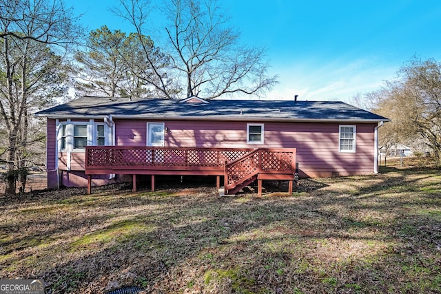 rear view of property with a wooden deck and a lawn