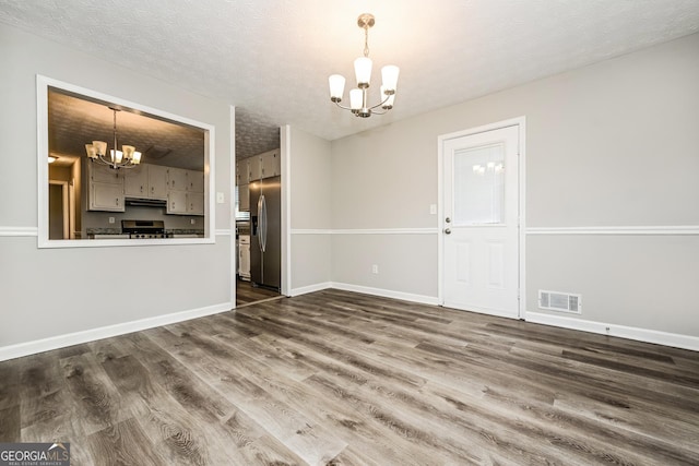 interior space with a notable chandelier, dark hardwood / wood-style floors, and a textured ceiling