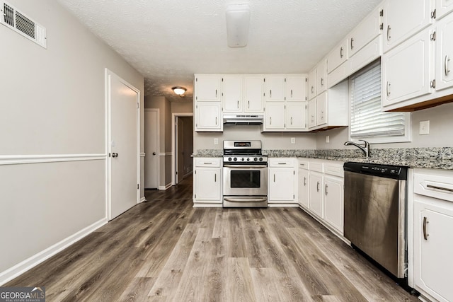 kitchen featuring light stone counters, stainless steel appliances, and white cabinets