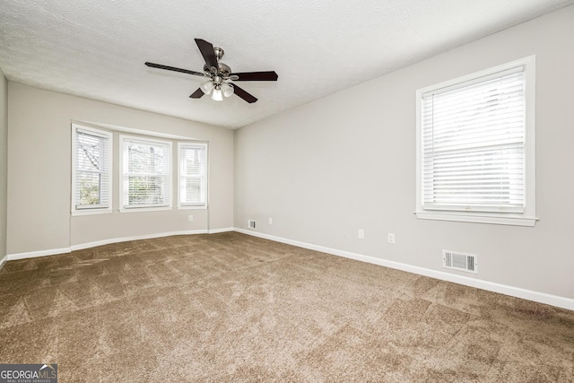 empty room with ceiling fan, carpet, and a textured ceiling