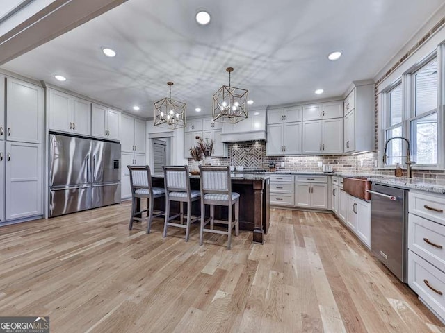 kitchen featuring a kitchen breakfast bar, hanging light fixtures, a center island, light stone counters, and stainless steel appliances