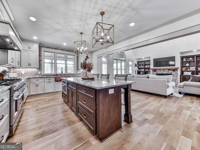 kitchen featuring white cabinetry, a kitchen bar, hanging light fixtures, double oven range, and a center island