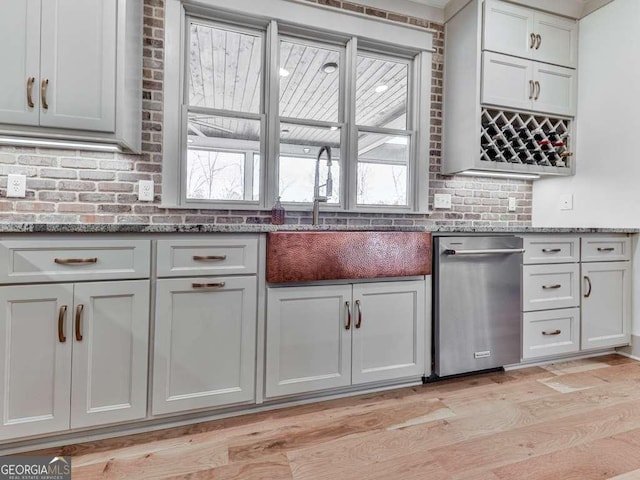 kitchen featuring stone countertops, sink, light wood-type flooring, and plenty of natural light