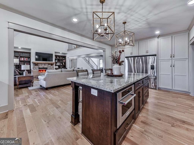 kitchen with decorative light fixtures, white cabinetry, a kitchen breakfast bar, a center island, and light stone counters