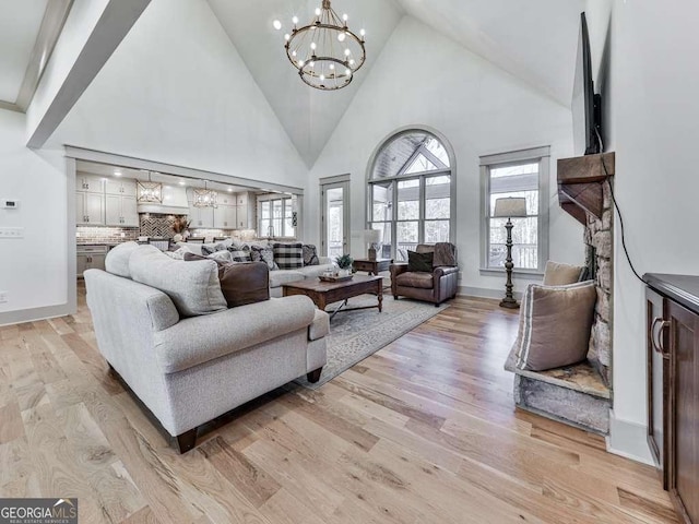 living room featuring an inviting chandelier, plenty of natural light, and light wood-type flooring