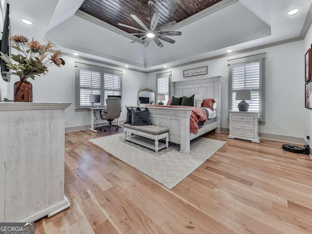 bedroom featuring crown molding, ceiling fan, a tray ceiling, and light hardwood / wood-style flooring