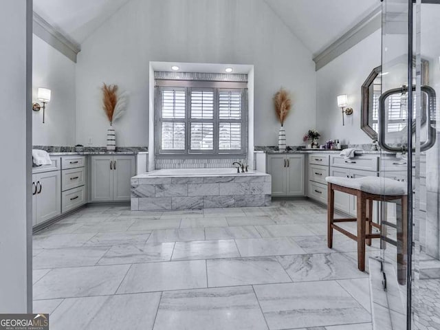 bathroom featuring vanity, tiled tub, and high vaulted ceiling