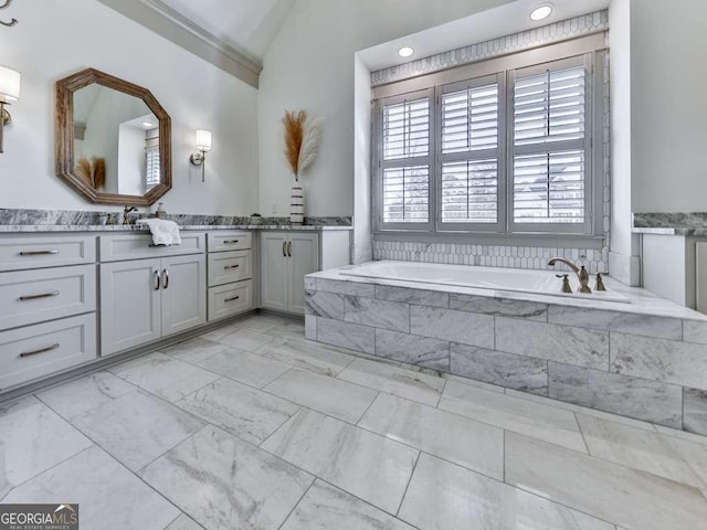 bathroom with vanity, lofted ceiling, and tiled bath